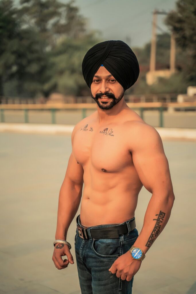 Fit shirtless man with a turban posing outdoors, showcasing muscular physique.